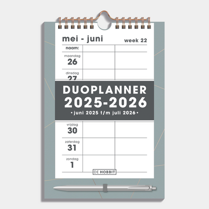 Duoplanner 2025 - 2026 A5 met goudfolielijnen op een grijsgroen bord met pen – vooraanzicht.