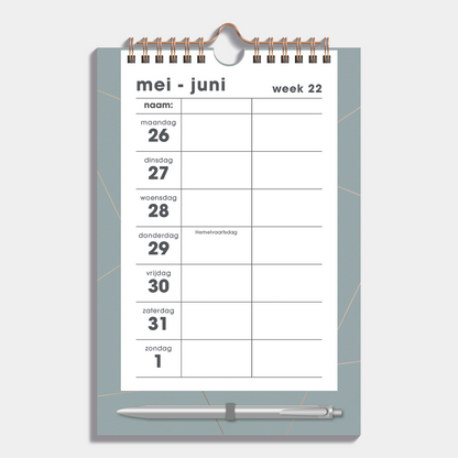 Duoplanner 2025 - 2026 A5 met goudfolielijnen op een grijsgroen bord met pen – binnenwerk met weekoverzicht.