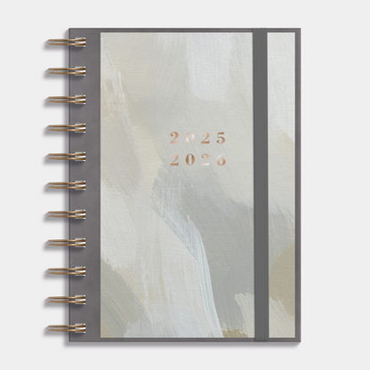 A6 ringband agenda 2025-2026 met grijsgroene verfstreken op insteekkaart, flexibele cover en elastische sluiting – vooraanzicht.